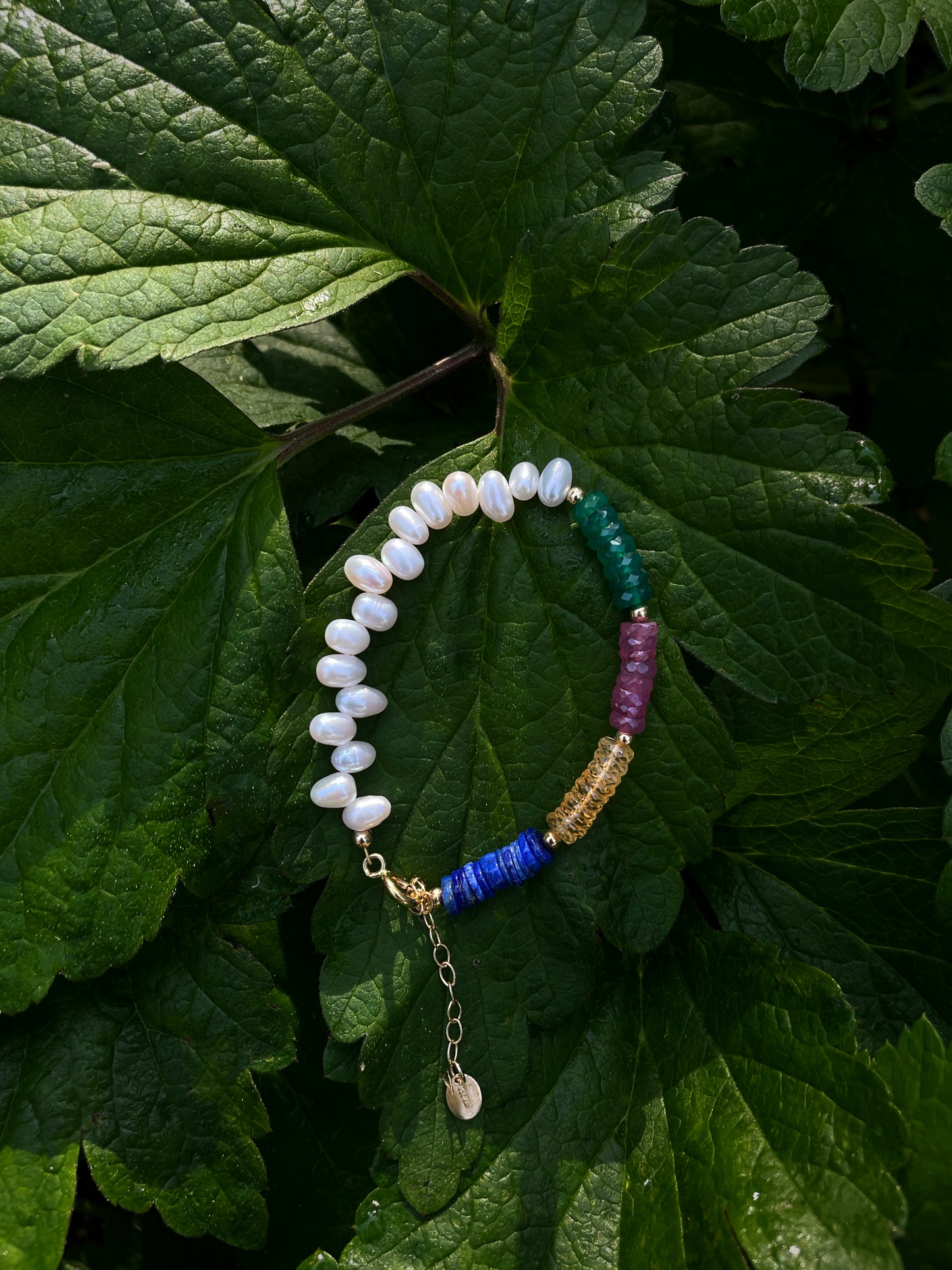 Asymmetric bracelet by monái featuring multicolored gemstones and a single baroque pearl – expressive, handcrafted luxury