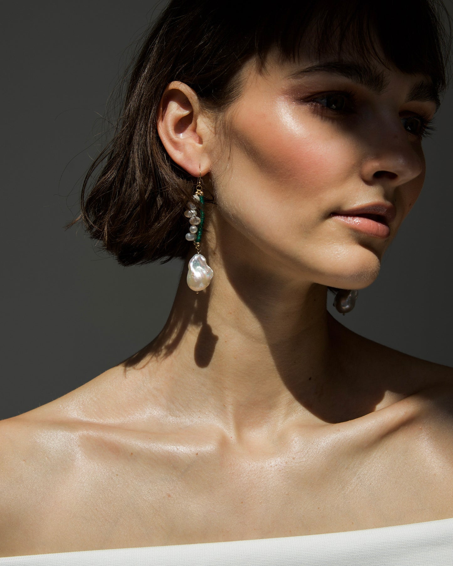 side view of monái earrings on model – luminous baroque pearl and green onyx dangle gracefully with sculptural movement