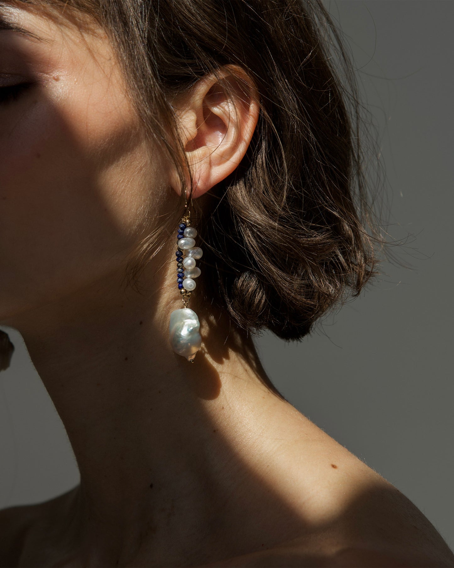 close-up of monái earrings showcasing AAA+ quality baroque pearls paired with hand-cut lapis lazuli and golden pyrite gemstones – a harmonious blend of organic form and vibrant color
