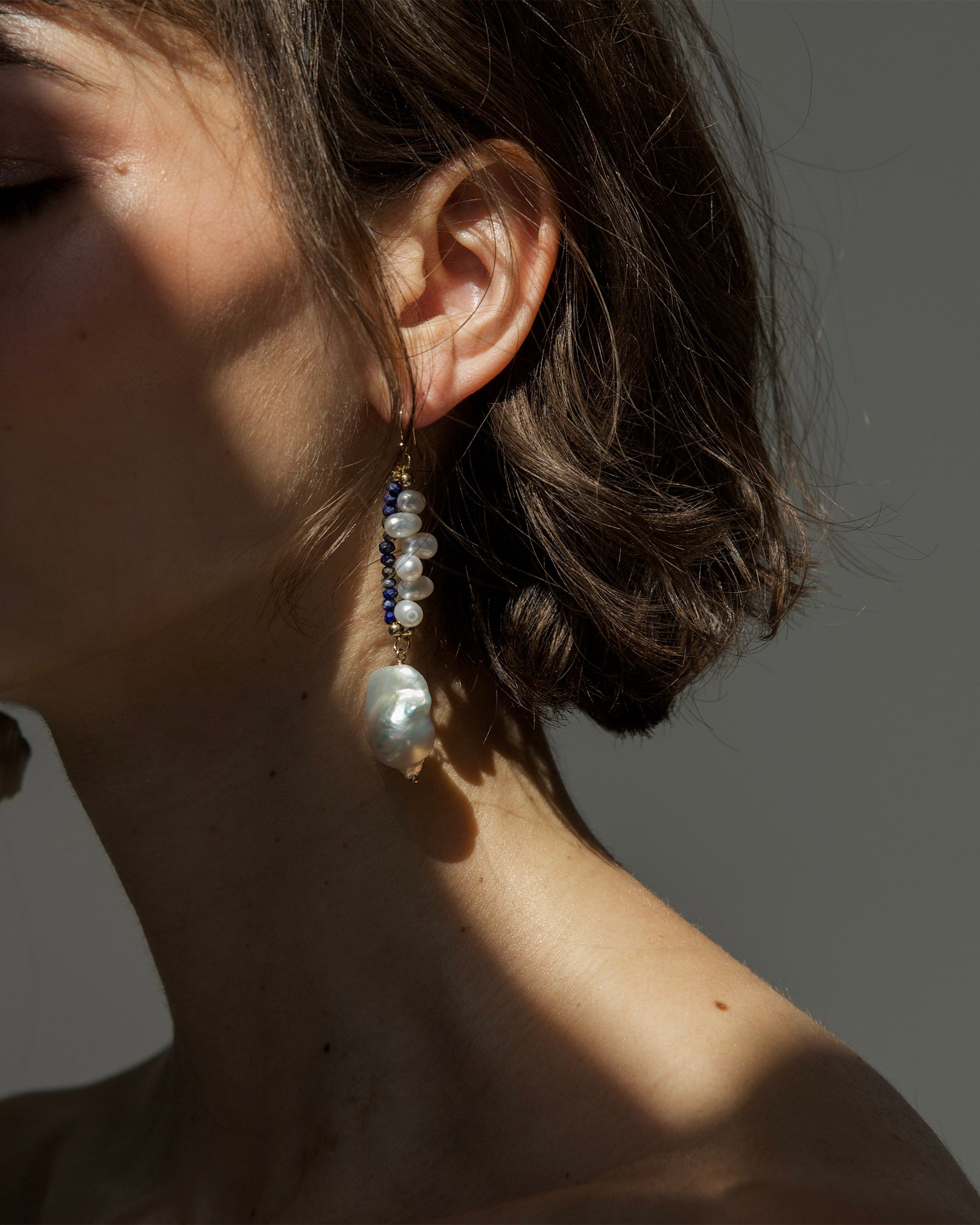 close-up of monái earrings showcasing AAA+ quality baroque pearls paired with hand-cut lapis lazuli and golden pyrite gemstones – a harmonious blend of organic form and vibrant color