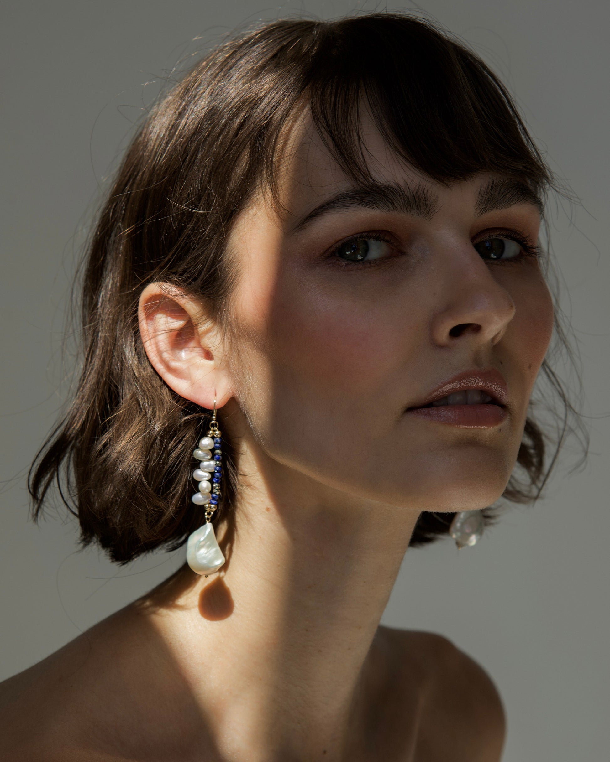 monái baroque pearl lapis lazuli earrings worn by model – statement jewelry combining natural elegance with bold design