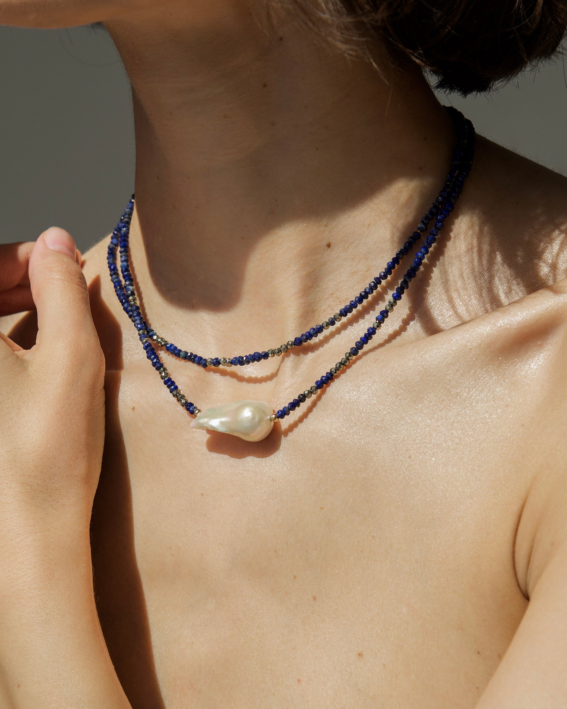 close-up of monái necklace with natural baroque pearl and hand-cut lapis lazuli – a balance of depth, contrast, and organic beauty