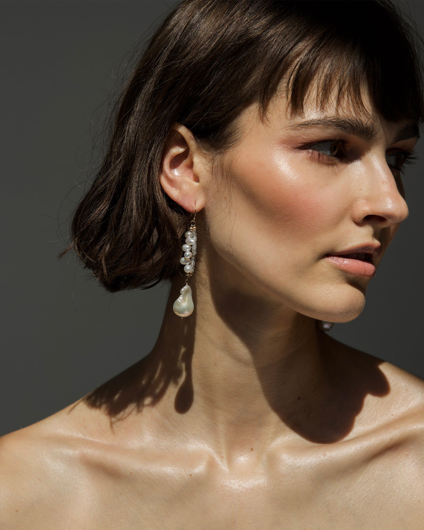 monái baroque pearl rainbow moonstone earrings worn by model – elegant drop earrings that enhance the neckline with iridescent stones and natural pearl detail