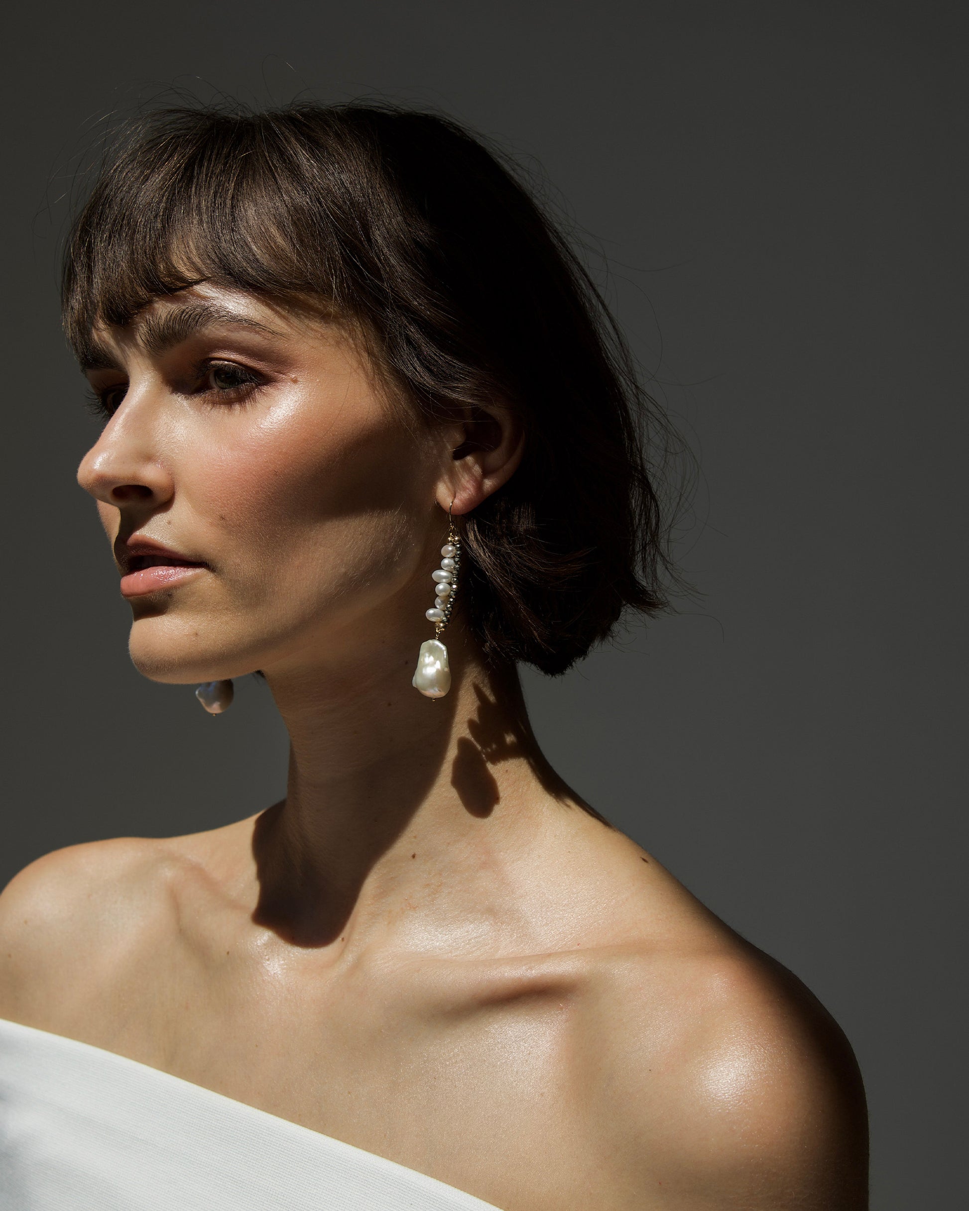 side profile of model wearing monái baroque pearl pyrite earrings – highlighting the earrings’ metallic gemstones and baroque-inspired elegance
