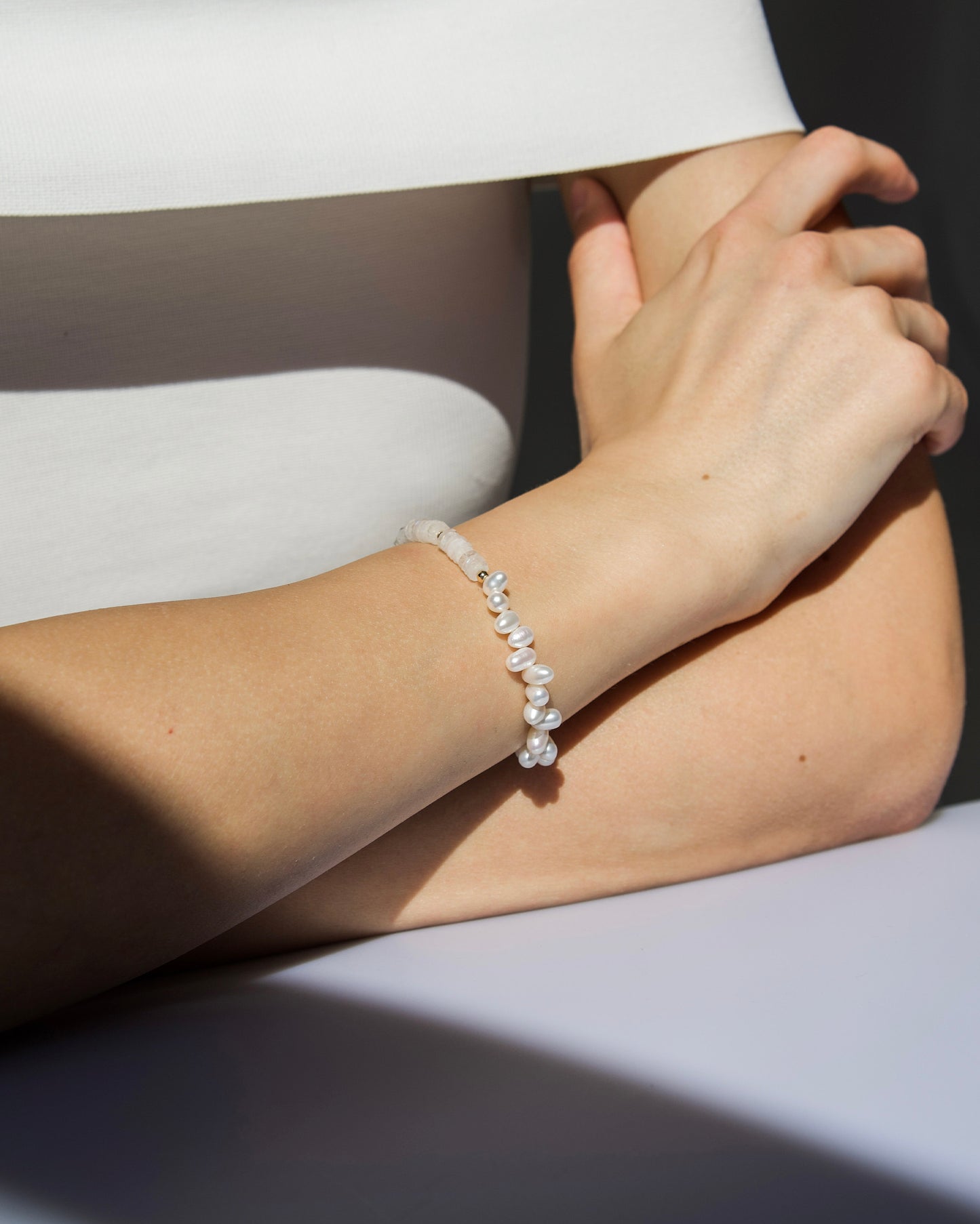 side profile of model wearing monái rainbow moonstone asymmetrical bracelet – highlighting the bracelet’s soft shimmer and baroque-inspired elegance
